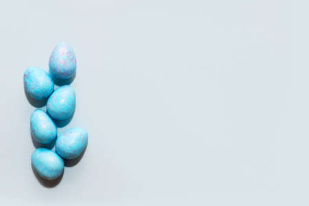 Blue lavender chocolate easter candy eggs on paper background.の写真素材