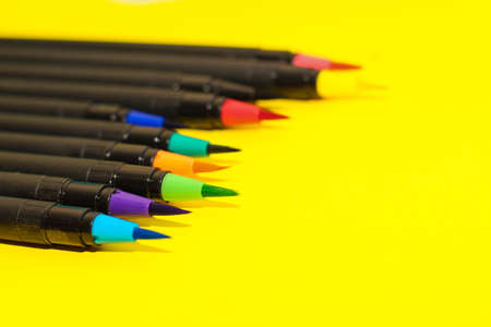 Multi-colored stationery felt-tip pens and brushes on a background of multi-colored cardboard paper.の写真素材