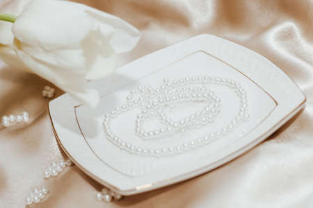 Bouquet of white tulips with pearl beads on silk golden nude satin background.の写真素材