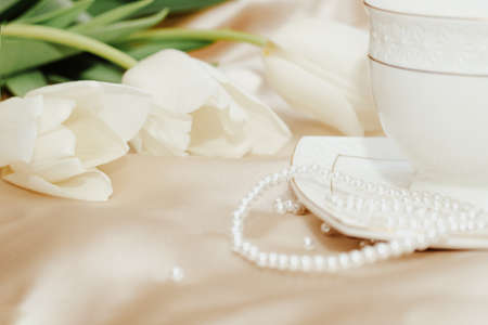 Bouquet of white tulips with pearl beads on silk golden nude satin background.の写真素材