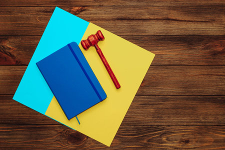Blue notepad diary with a judge's gavel on a wooden table, colors of the flag of Ukraine.の写真素材