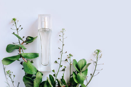 Glass transparent perfume bottle with green plants.