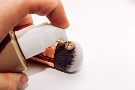 Foundation brush and foundation in a jar on a light background.