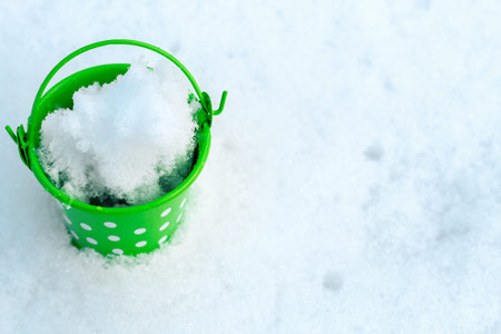 Green iron small bucket on snow background.の写真素材
