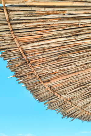 Straw beach umbrellas on a background of blue sky, vacation concept.の写真素材