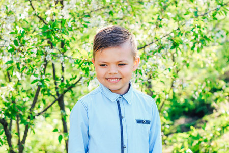 Boy in a shirt smiling against the background of flowering trees.の写真素材