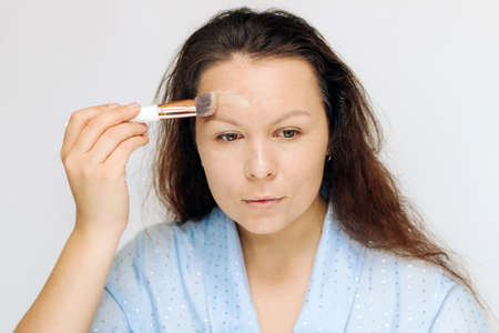 The girl applies a tonal corrective cream on a problematic pigmentation face.の写真素材