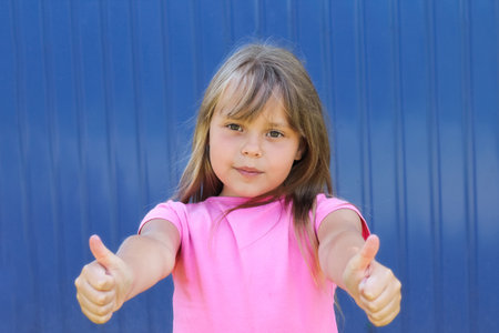 Young girl child in pink t-shirt portrait shows thumbs up.の写真素材