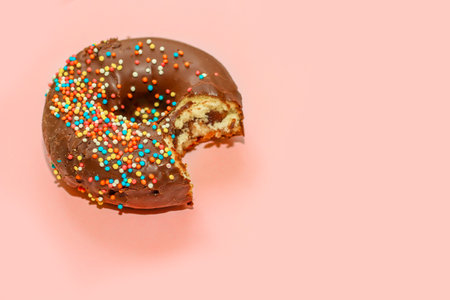 Donuts with chocolate glaze and colored sprinkles of round shape on a colored backgroundの写真素材