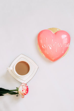 Pink tea rose with heart shaped pink mousse cake with a cup of coffee.の写真素材