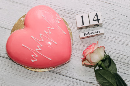 Pink tea rose with heart shaped pink mousse cake and February 14 calendar.の写真素材