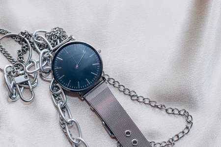 Stylish silver chain decorations for the neck and watch on a silk shiny background.の写真素材