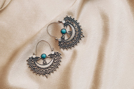 Ethnic stylish earrings jewelry on a silk golden background.の写真素材