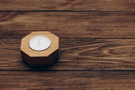 Wax and aromatic candle in a wooden candlestick stands on a wooden table.の写真素材