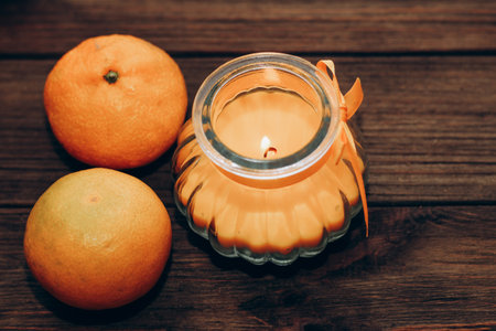 Wax and aromatic orange candle in a candlestick stands on a wooden table.の写真素材