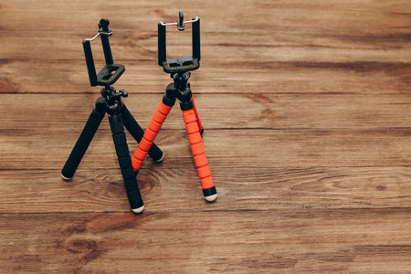 Two manual tripod monopods for a phone or a small camera on a wooden table.の写真素材