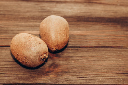 Fluffy fruits two kiwis lie on a wooden brown table.の写真素材