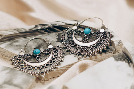 Ethnic stylish earrings jewelry on a silk golden background.の写真素材