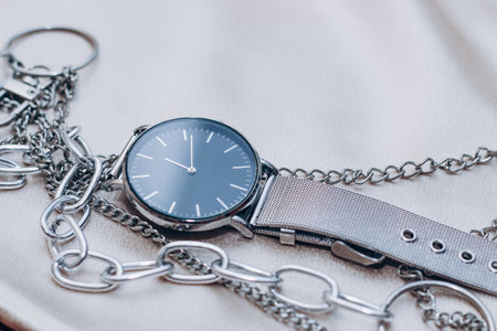 Stylish silver chain decorations for the neck and watch on a silk shiny background.の写真素材