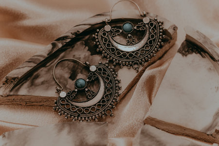 Ethnic stylish earrings jewelry on a silk golden background.の写真素材