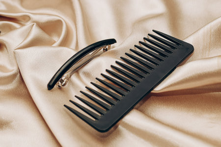 Elegant black hair clip and comb on a silk golden background.の写真素材