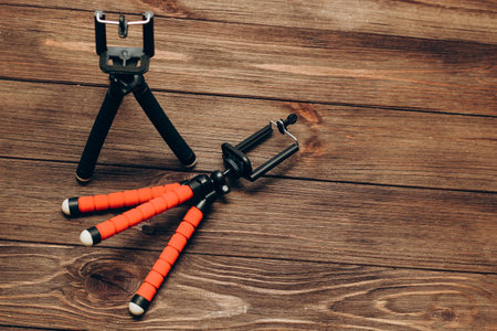 Two manual tripod monopods for a phone or a small camera on a wooden table.の写真素材