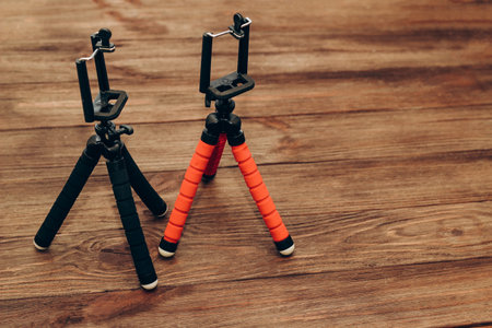 Two manual tripod monopods for a phone or a small camera on a wooden table.の写真素材