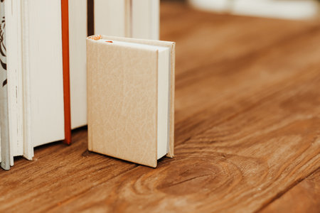 A stack of books stand on the tables, stacked in the frame, next to small mini books.の写真素材