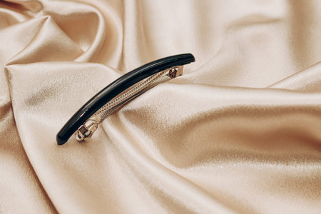 Elegant black hair clip on a silk golden background.の写真素材