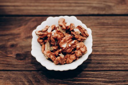 Dried walnut grains in a bowl on a wooden table.の写真素材