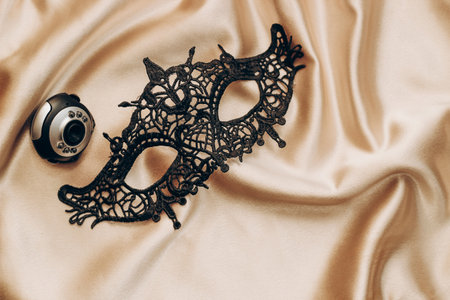 Sexy black lace stylish masquerade mask and webcam on golden silk sheet, web modeling concept.の写真素材