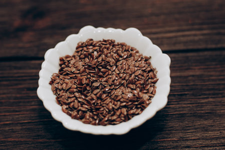 Dried flax seeds in a bowl on a wooden table.の写真素材