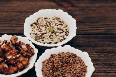 A mixture of sunflower, pumpkin and flax seeds with nuts in a bowl on a wooden table.の写真素材
