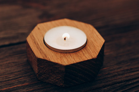 Wax and aromatic candle in a wooden candlestick stands on a wooden table.の写真素材
