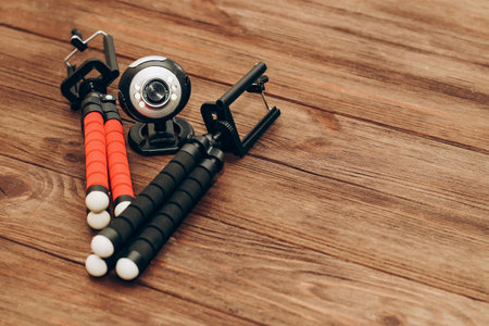Two manual tripod monopods for a phone or a small camera on a wooden table.の写真素材