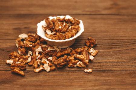Dried walnut grains in a bowl on a wooden table.の写真素材