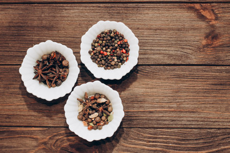 Spices anise, pepper, cumin, cumin, ginger in bowls on a wooden table.の写真素材