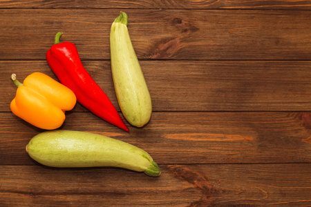 Red pepper Kapi with yellow sweet pepper and zucchini on a wooden background, space for text.の写真素材