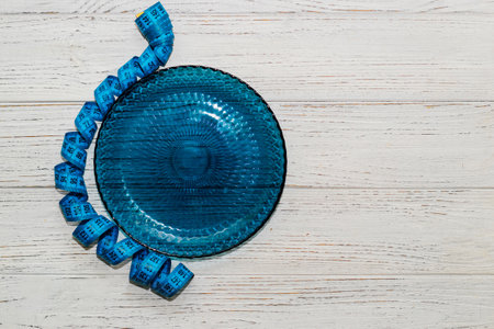 empty blue plate with centimeter on background, diet proper nutrition concept.の写真素材