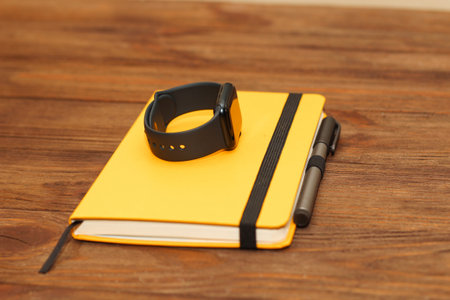 A black technological smart watch lies on a notepad for time management.の写真素材