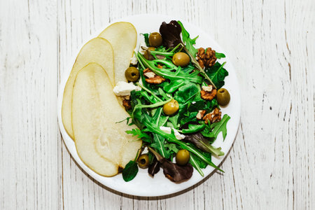Salad with pears, herbs, arugula, prosciutto, cheese, green olives and nuts.の写真素材