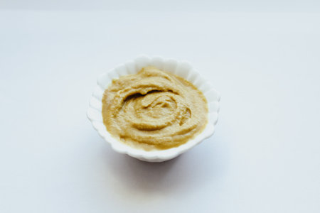 Mustard sauce in a white bowl on a white table.の写真素材