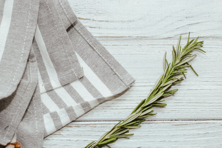 Fresh green sprig of rosemary seasoning on table with kitchen towel.の写真素材