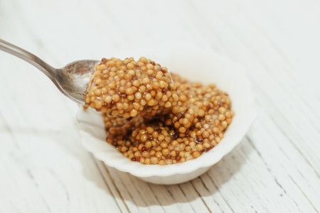 grain mustard in a white bowl on a white table.の写真素材