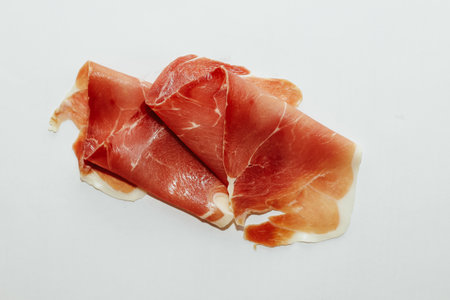 Pieces of dried pork jamon prosciutto on a white background.の写真素材