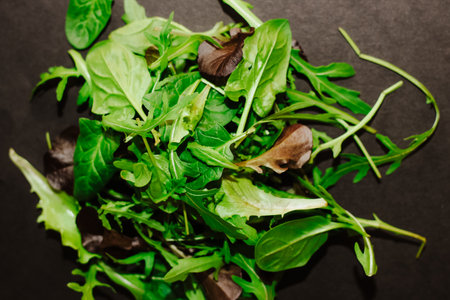Mix of lettuce leaves different types on black table.の写真素材