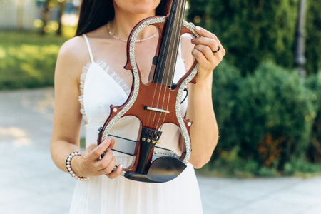 A fragment of an electric violin, a violin in the hands of a musician's girlの写真素材
