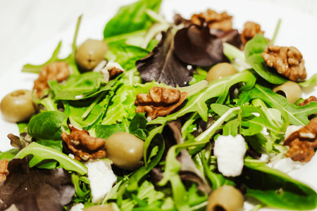 Salad leaves with arugula, cheese, green olives and nuts in a plate, healthy diet salad.の写真素材