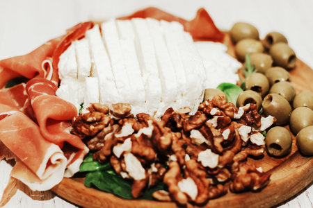 Pieces of dried pork jamon prosciutto with olives and cheese and nuts on the board.の写真素材