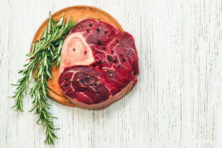 Fresh piece of meat large beef steak on the bone ossobuco with pepper, rosemary on the board.の写真素材